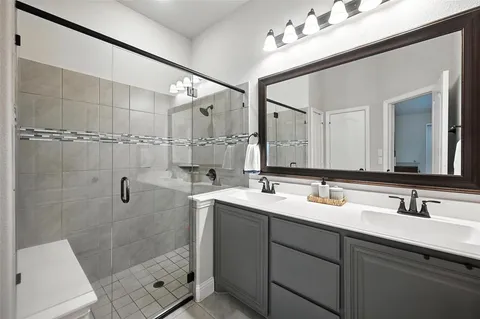 a bathroom with a double vanity sink mirror and shower