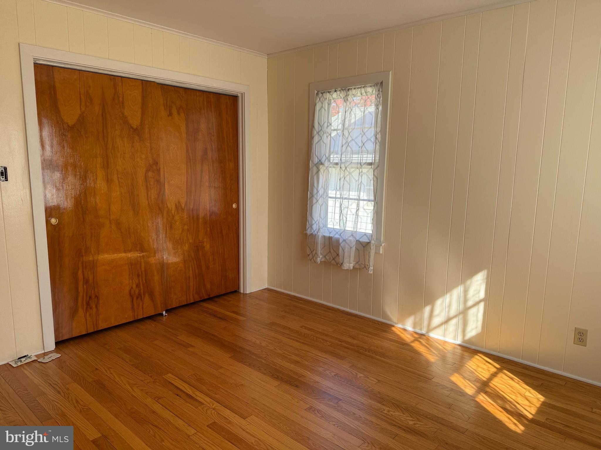 34 Townsend Avenue Bridgeton, NJ 08302 - Photo 13 of 23 an empty room with wooden floor and windows with curtains