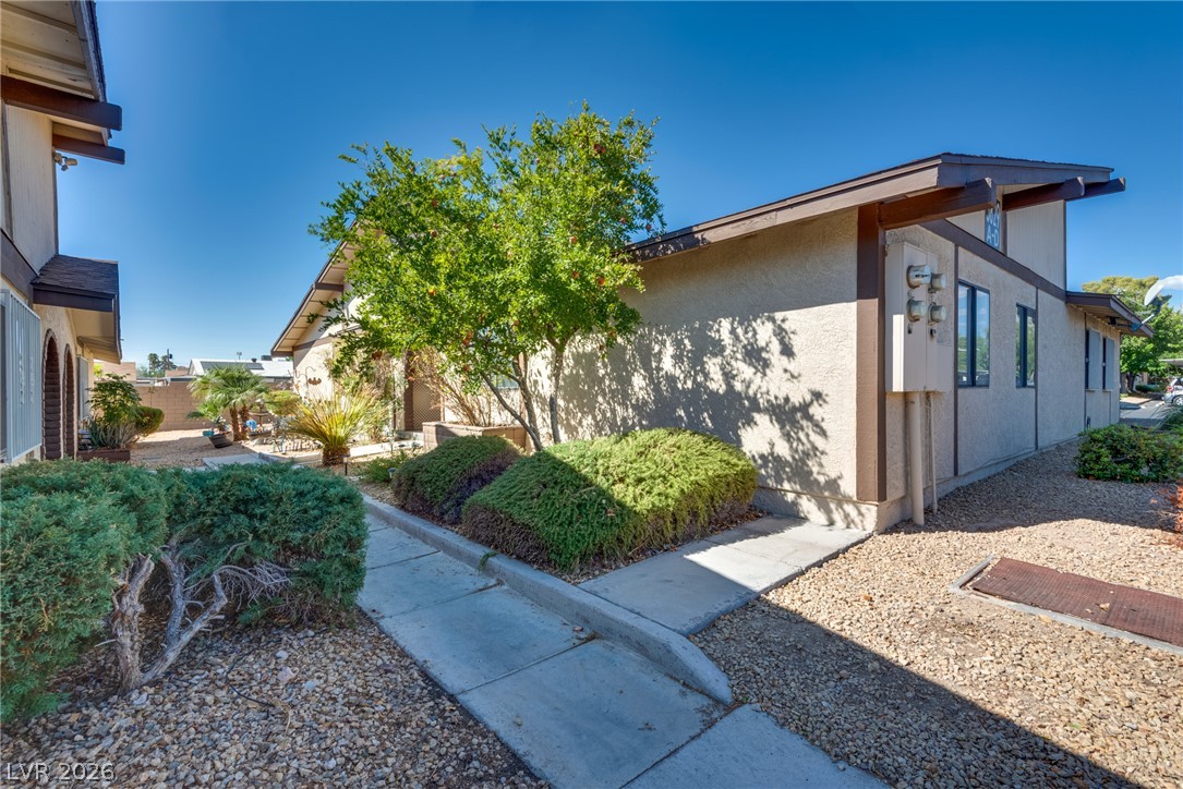 Concrete walkways meander through low-maintenance desert landscaping alongside the stucco exterior.