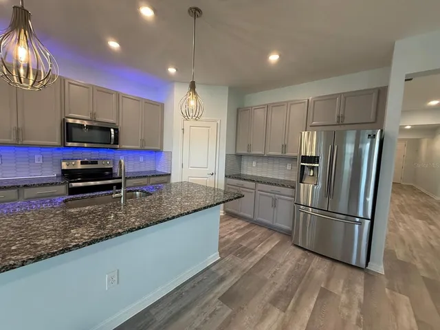 a kitchen with stainless steel appliances granite countertop a refrigerator a sink and a stove