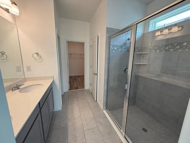 a bathroom with a granite countertop shower sink and mirror
