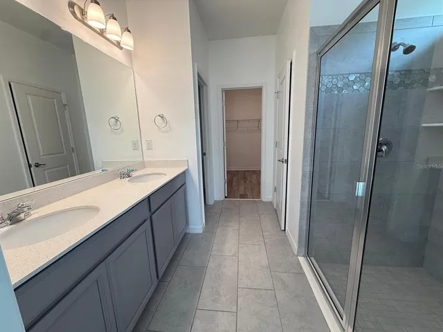 a bathroom with a double vanity sink and mirror with shower