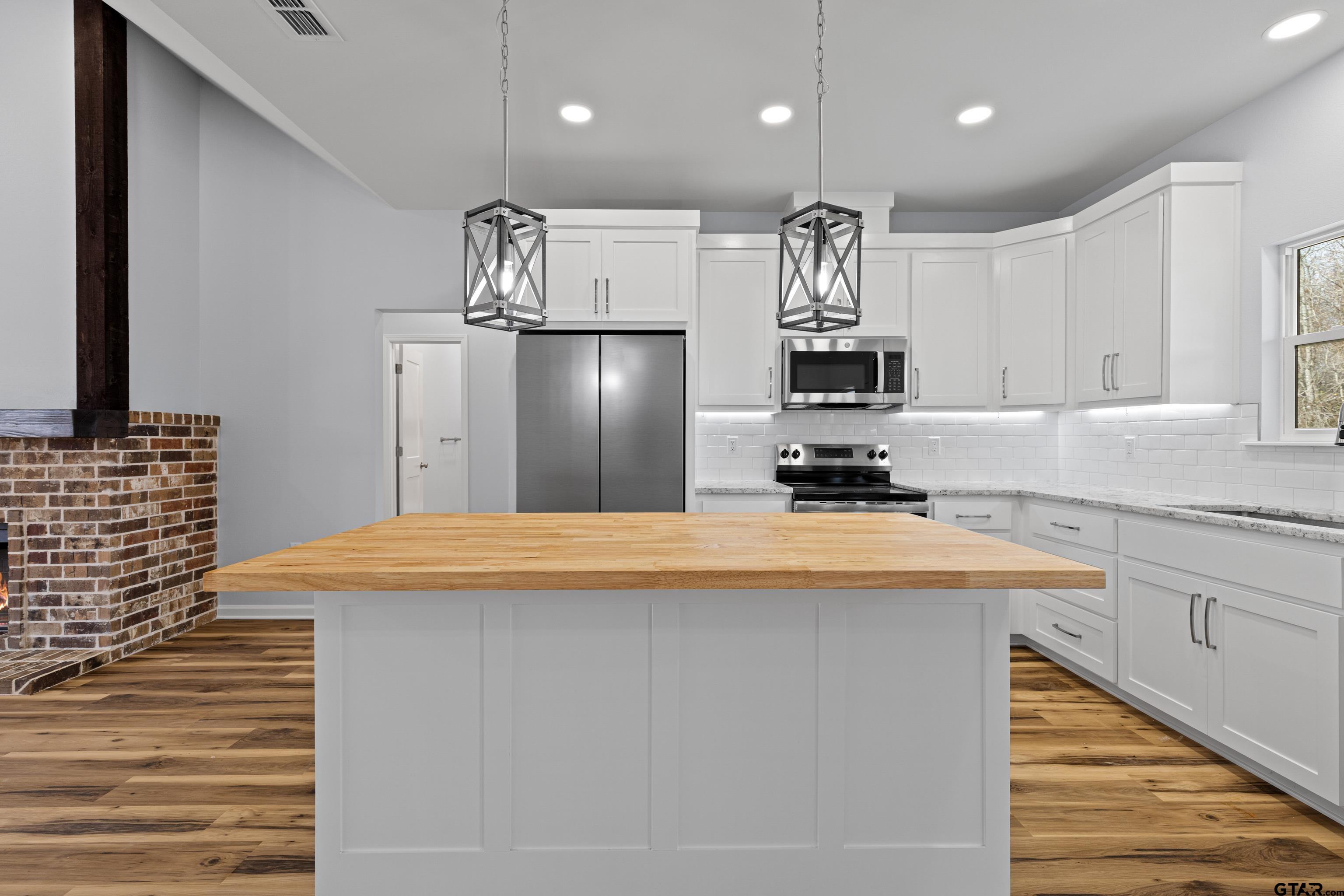 9934 Bob O Link Road Gladewater, TX 75647 - Photo 15 of 37 a kitchen with kitchen island a refrigerator stove and white cabinets