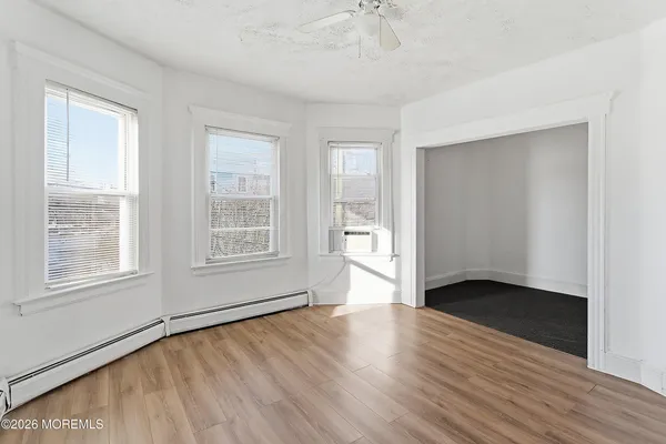 an empty room with wooden floor and windows