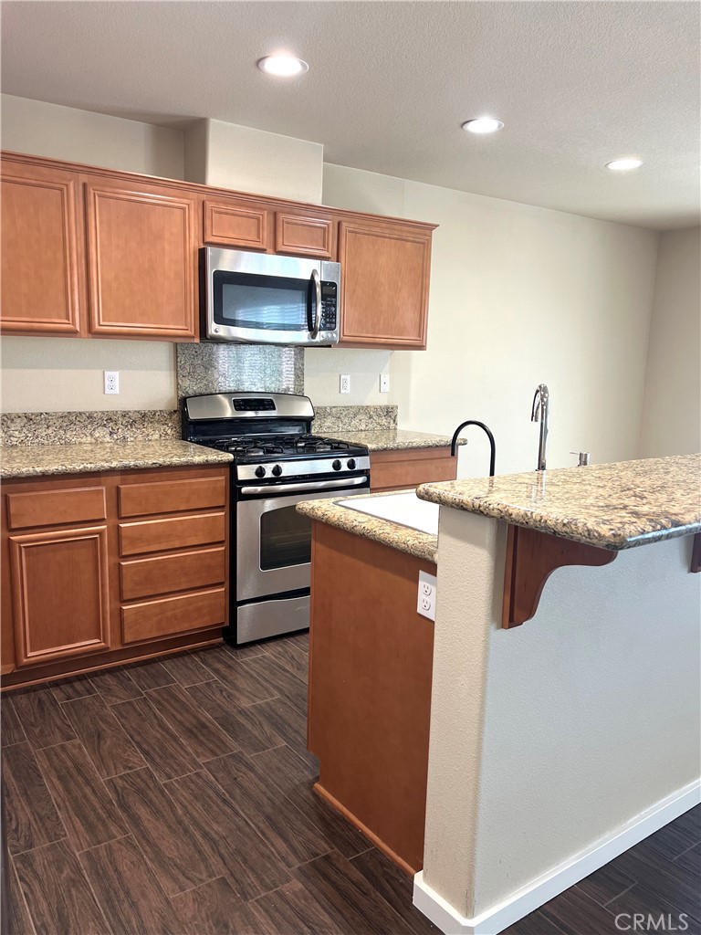 15765 Gable Street Victorville, CA 92394 - Photo 5 of 12 a kitchen with stainless steel appliances granite countertop a sink a stove a microwave and cabinets