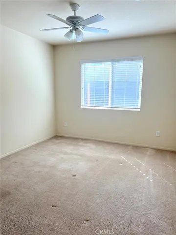 an empty room with a window and a fan