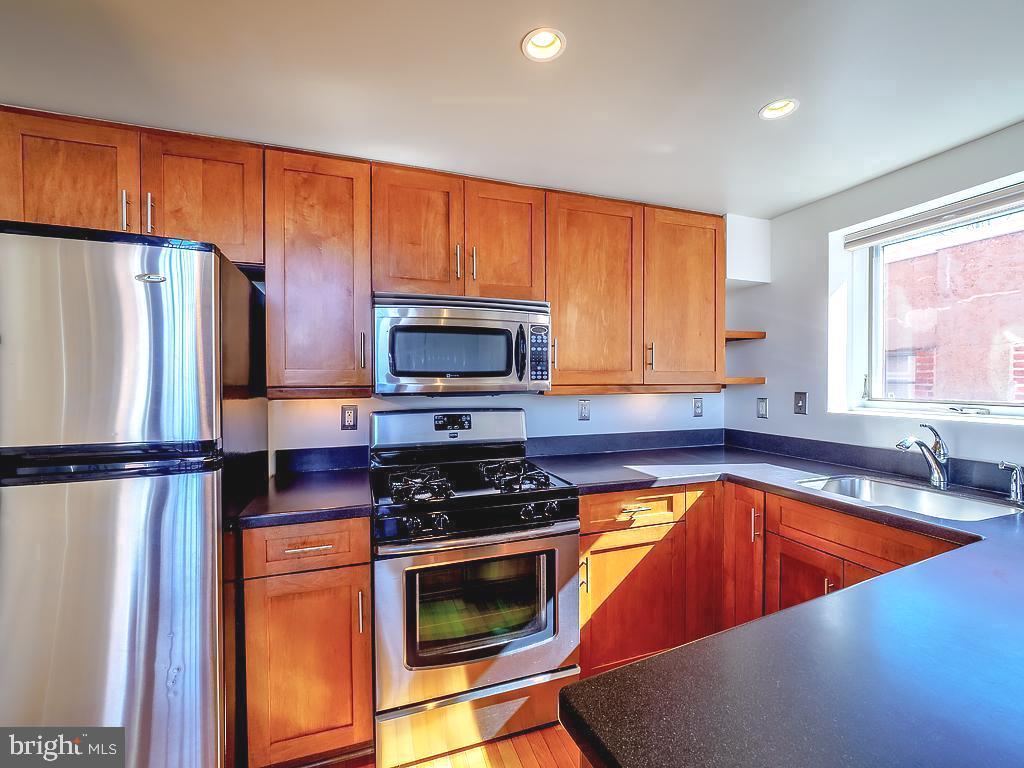 1530 14th Street Northwest, Unit 3B Washington, DC 20005 - Photo 7 of 28 a kitchen with a refrigerator a stove top oven a sink and cabinets