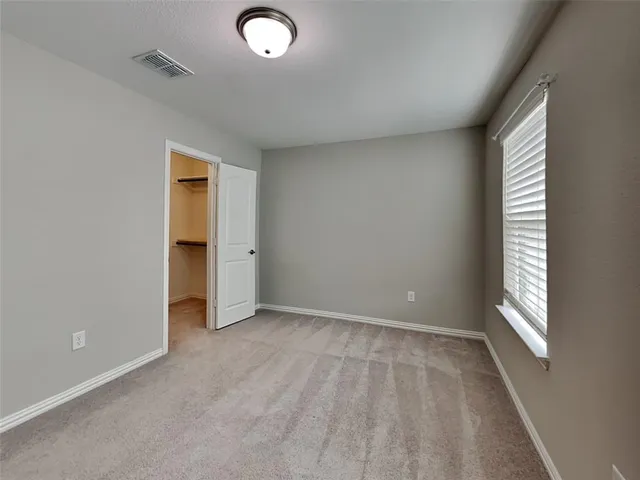 an empty room with a window and a kitchen