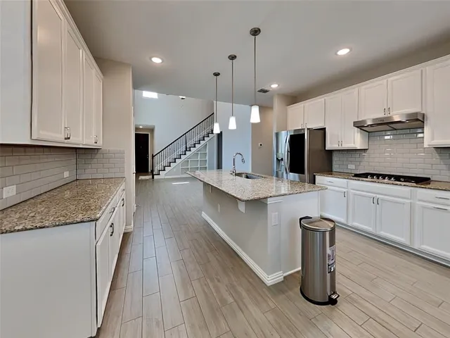 a kitchen with stainless steel appliances granite countertop a sink a stove and a wooden floor