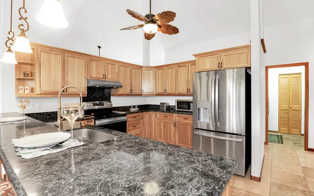 a kitchen with stainless steel appliances granite countertop a sink a stove a refrigerator a dining table and chairs with wooden floor