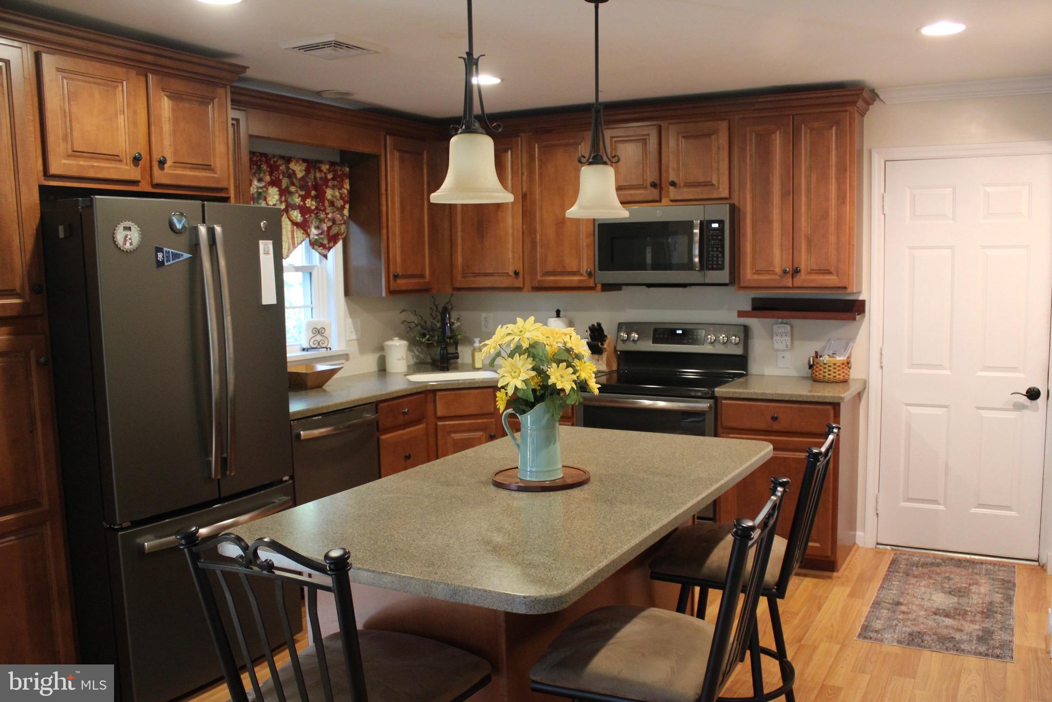 5331 Strasburg Road Kinzers, PA 17535 - Photo 8 of 31 a kitchen with stainless steel appliances granite countertop a stove a refrigerator a sink a dining table and chairs with wooden floor