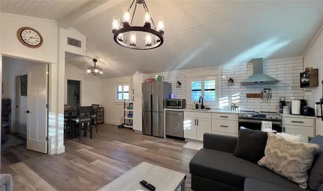 a kitchen with stainless steel appliances granite countertop a refrigerator a stove a sink dishwasher a dining table and chairs with wooden floor