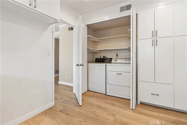 a view of a kitchen with white cabinets and wooden floor