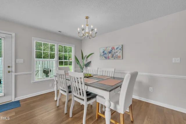 a view of a dining room with furniture a chandelier and wooden floor
