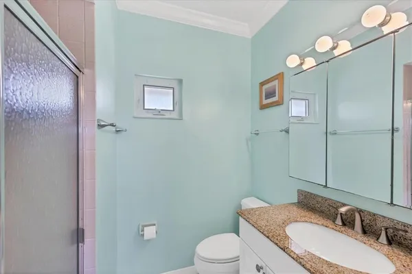 a bathroom with a granite countertop sink toilet and mirror