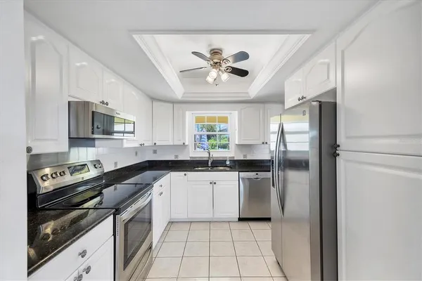 a kitchen with a refrigerator a sink a stove top oven and cabinets