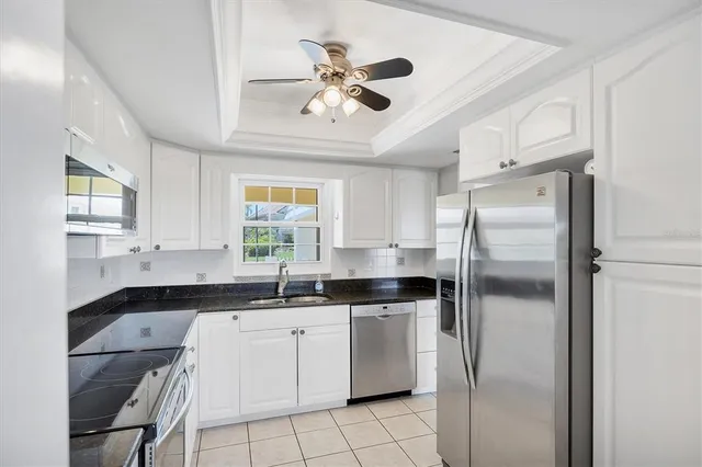 a kitchen with a sink stainless steel appliances cabinets and a window