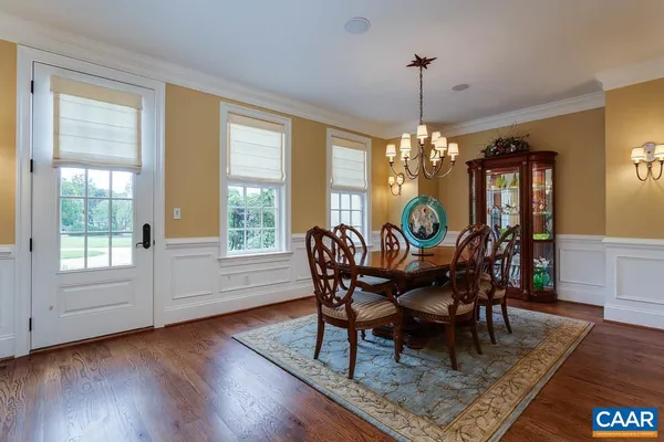 a kitchen with stainless steel appliances granite countertop a stove a sink dishwasher a dining table and chairs with wooden floor