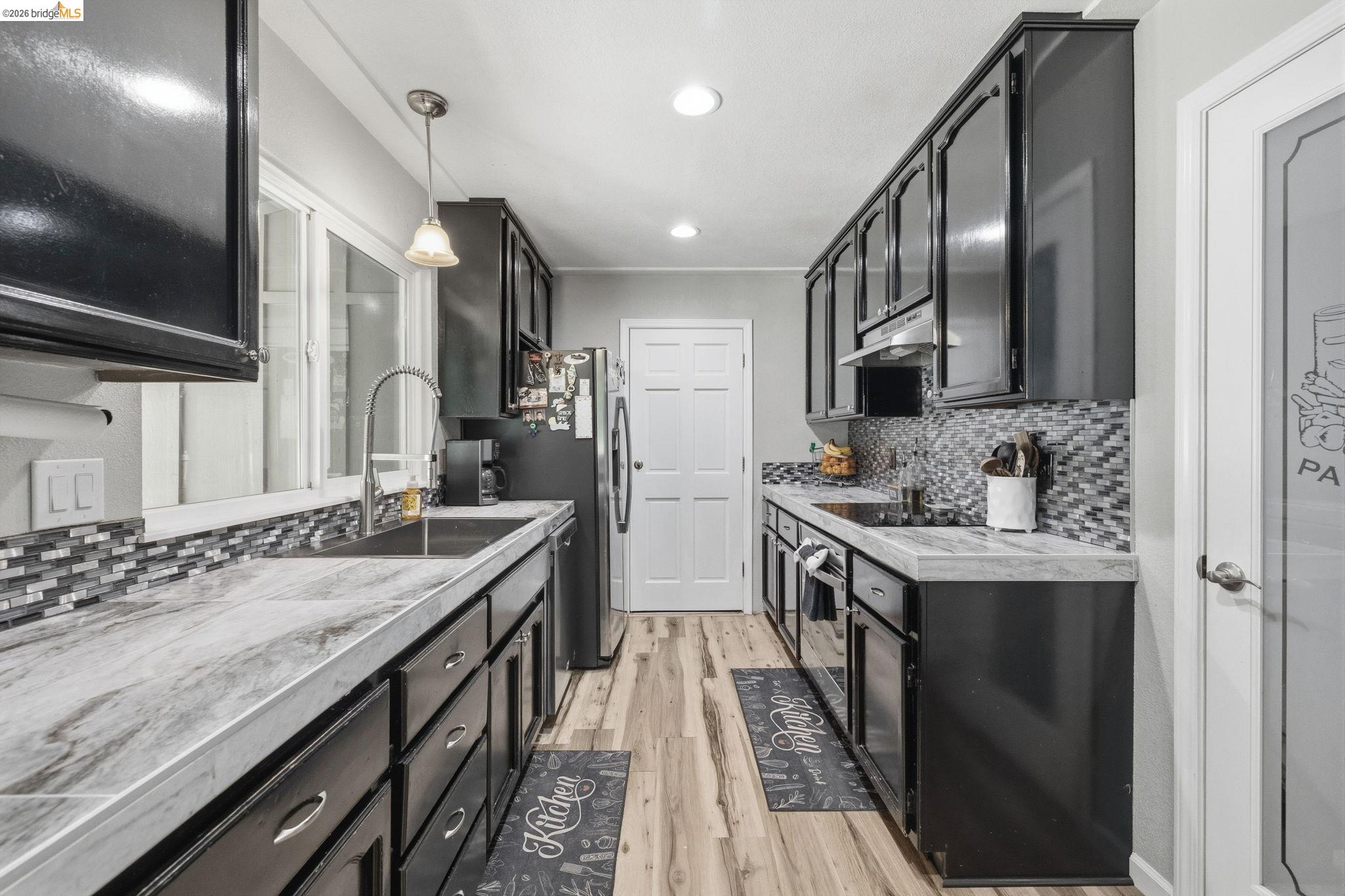 19059 Raboul Court Groveland, CA 95321 - Photo 9 of 21 Galley kitchen featuring dark cabinetry, stone-look countertops, and a mosaic tile backsplash