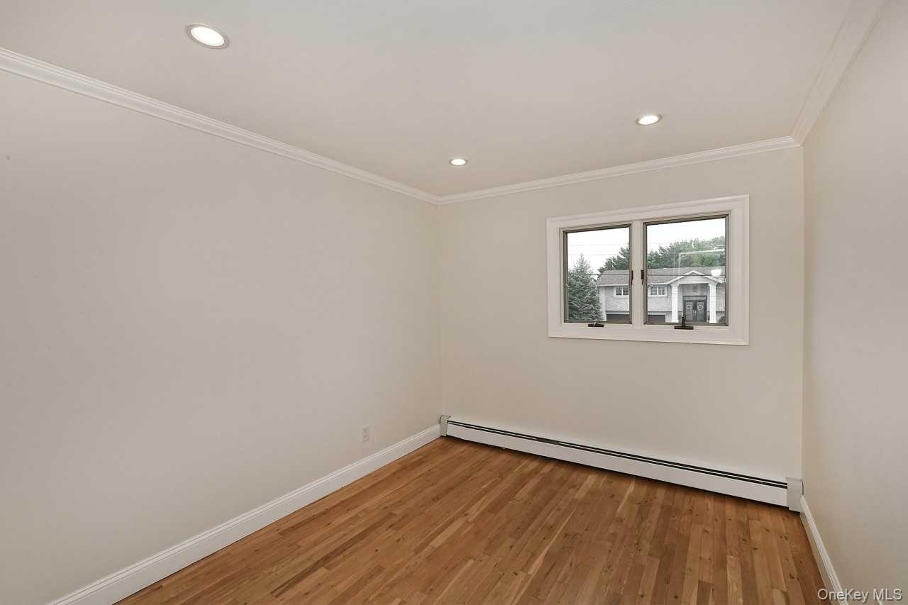 107 Beverly Road Massapequa, NY 11758 - Photo 17 of 41 a view of empty room with wooden floor and fan