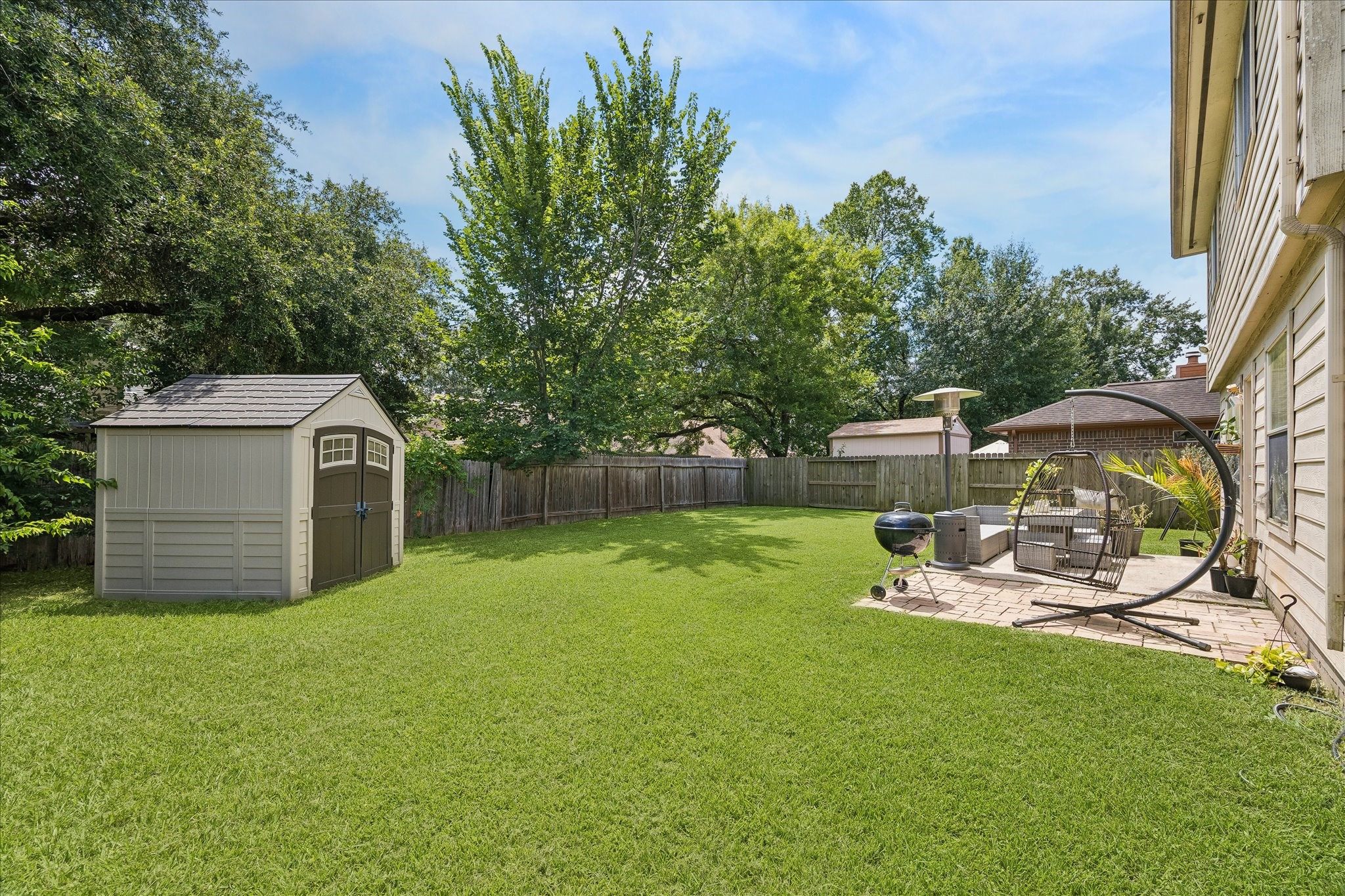 23234 Grand Rapids Lane Spring, TX 77373 - Photo 27 of 30 Sprawling backyard oasis features a storage shed, patio seating area, and mature trees offering shade and privacy.