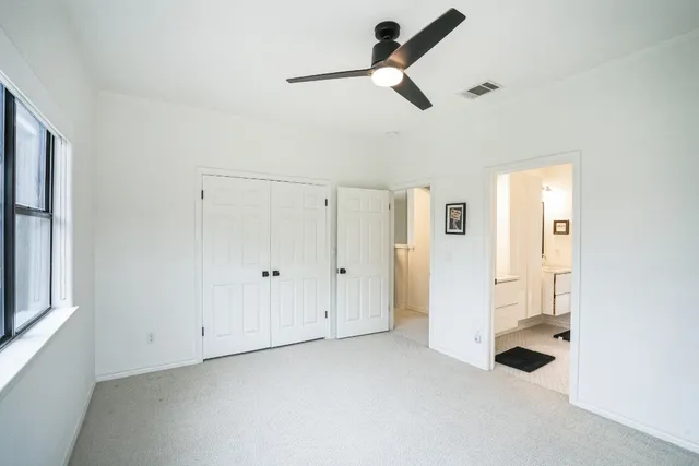 an empty room with windows and fan