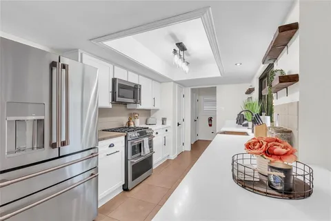 a kitchen with stainless steel appliances granite countertop a refrigerator a stove a sink dishwasher and white cabinets with wooden floor