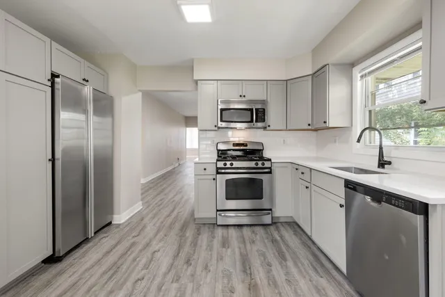 a kitchen with cabinets stainless steel appliances and wooden floor