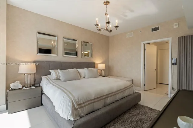 a spacious bedroom with a bed and a chandelier