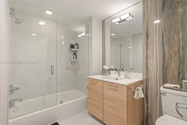 a bathroom with a sink a toilet a mirror and shower