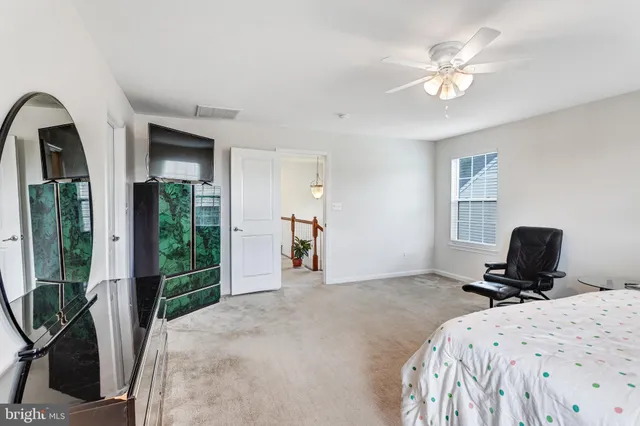 a bedroom with a bed a large mirror and a flat tv screen on dresser
