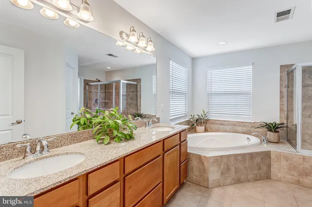 a spacious bathroom with a granite countertop double vanity sink a large mirror and a bathtub