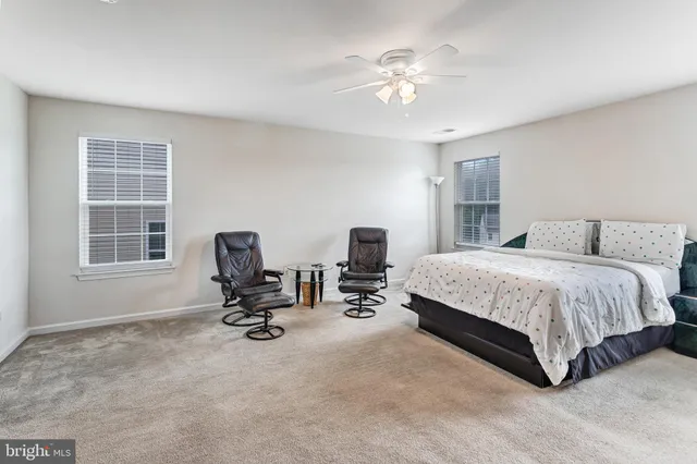 a spacious bedroom with a bed a chair and a chandelier