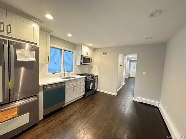 a large kitchen with a refrigerator a sink a stove and cabinets