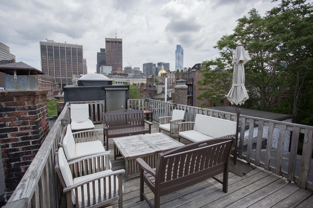a view of a roof deck with couches chairs and wooden floor
