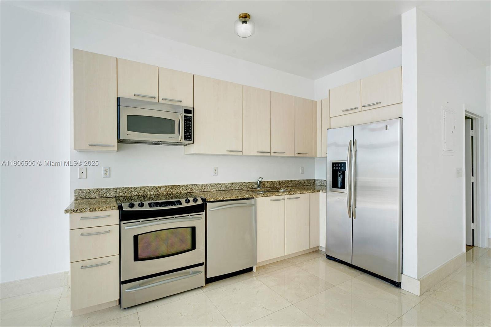 2001 Meridian Avenue, Unit 516 Miami Beach, FL 33139 - Photo 4 of 26 a kitchen with white cabinets and stainless steel appliances