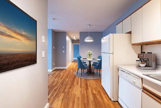 a kitchen view with a dining table chairs refrigerator and sink