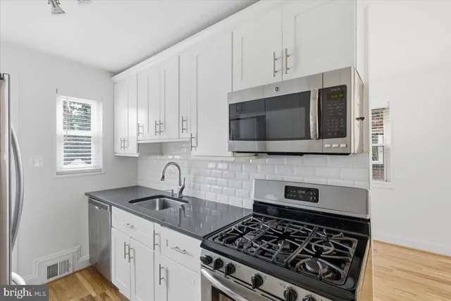 a kitchen with stainless steel appliances granite countertop a sink stove and microwave