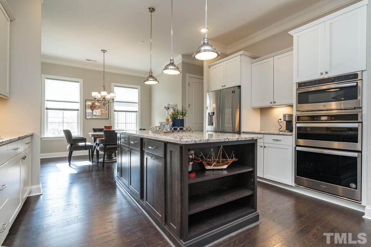 129 Damsire Way Cary, NC 27513 - Photo 8 of 32 a kitchen with stainless steel appliances granite countertop a stove refrigerator and a dining table with wooden floor