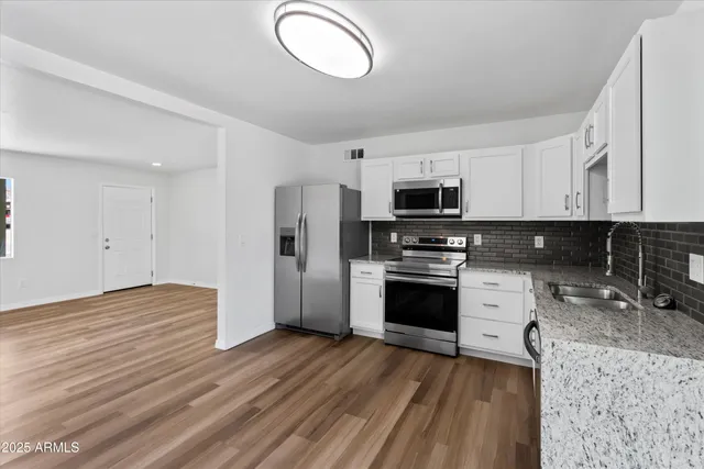 a kitchen with granite countertop a refrigerator stove and sink