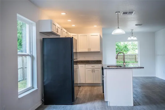 a kitchen with kitchen island wooden floors cabinets and a window