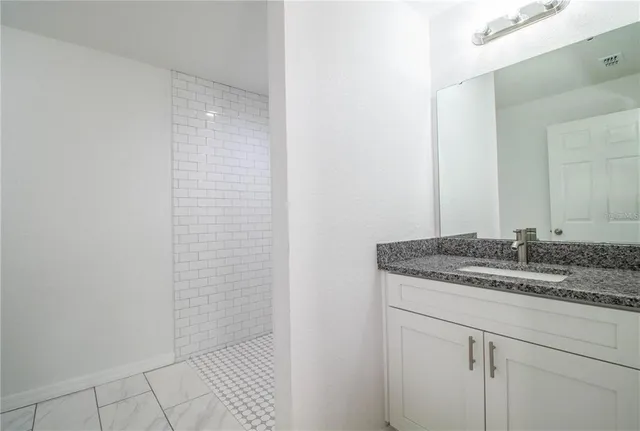 a bathroom with a granite countertop sink and a mirror
