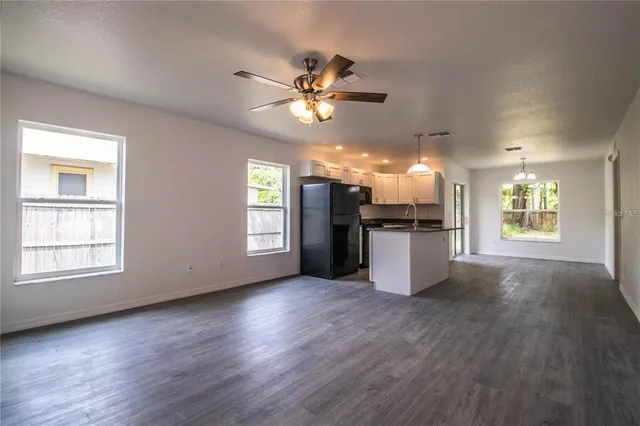 an empty room with wooden floor a ceiling fan and windows