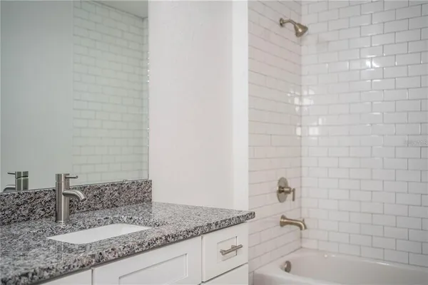 a bathroom with a granite countertop sink and a bathtub