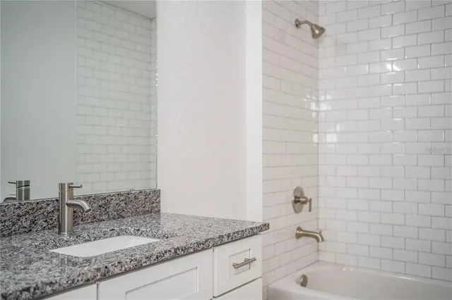 a bathroom with a granite countertop sink and a bathtub