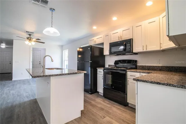 a kitchen with stainless steel appliances granite countertop a stove top oven a sink and a microwave