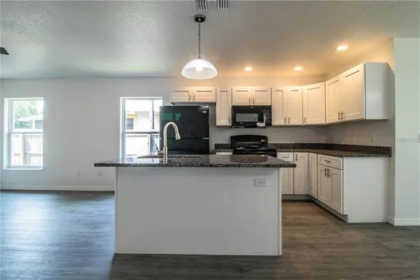 a kitchen with stainless steel appliances granite countertop a sink a stove a microwave a center island and cabinets