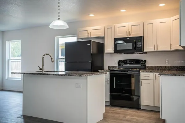 a kitchen with stainless steel appliances granite countertop a stove a sink and a microwave