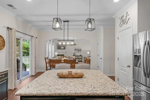a living room with stainless steel appliances granite countertop furniture and a chandelier