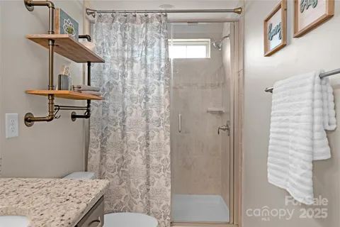 a bathroom with a granite countertop sink a toilet and shower